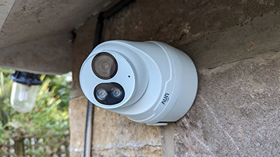 security camera mounted on a stone wall with lenses visible and a blurred background