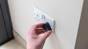 A man plugging in a plug into a UK socket